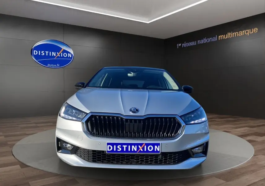 Vue frontale d'une Skoda Fabia gris clair avec calandre noire et phares LED dans un showroom.