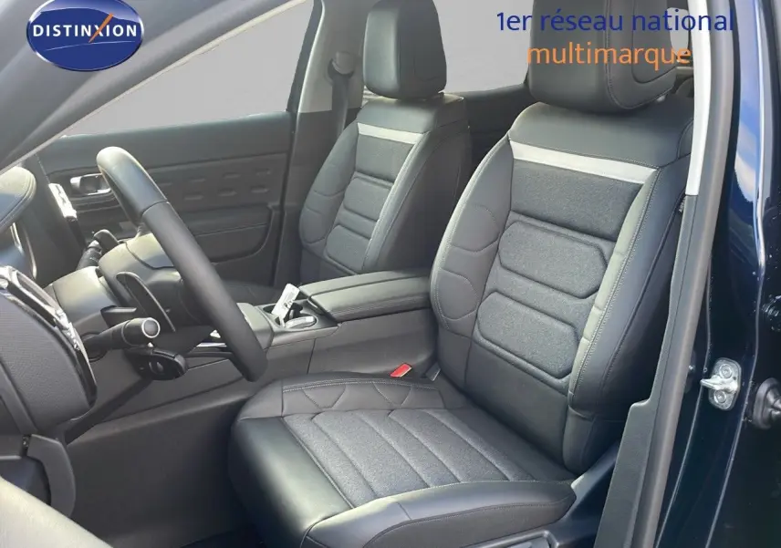 Intérieur avant du Citroën C5 Aircross 2025 bleu Eclipse Metal, sièges en cuir noir et tissu gris, volant visible côté gauche.