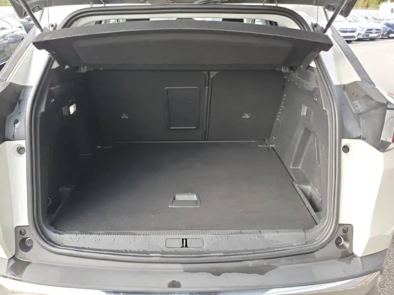 Coffre ouvert vu de l'arrière d'un Peugeot 3008 blanc nacré, montrant un espace de chargement spacieux et propre.