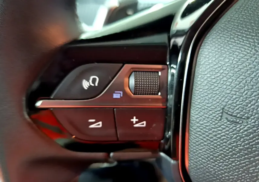 Gros plan sur les commandes multifonctions du volant cuir noir du Peugeot 2008, avec boutons de volume et appel.