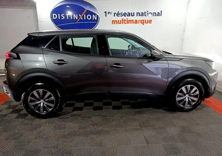Peugeot 2008 gris clair vue de profil côté gauche dans un showroom avec logo Distinxion en arrière-plan.