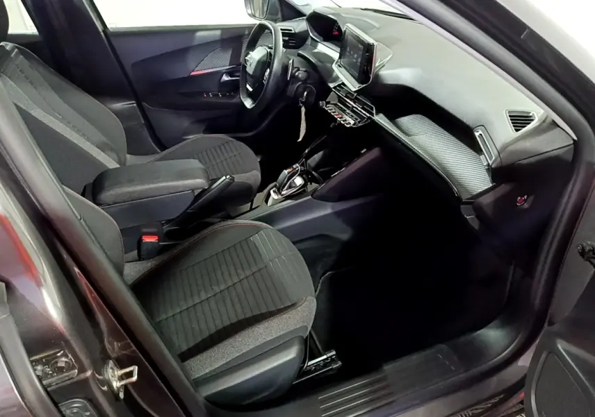 Vue intérieure côté conducteur de la Peugeot 2008 gris clair, avec volant cuir multifonctions et écran tactile central.