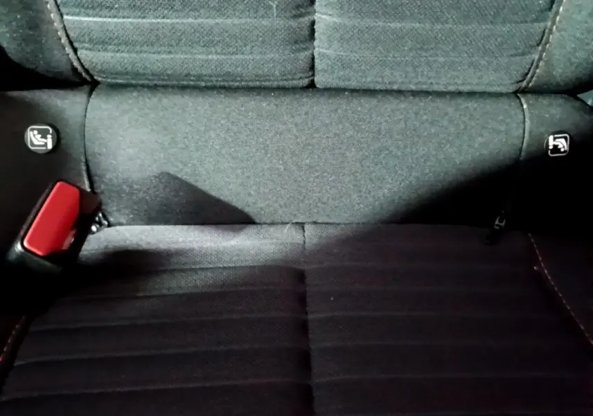 Gros plan sur la banquette arrière noire du Peugeot 2008, montrant les fixations Isofix et la ceinture rouge.