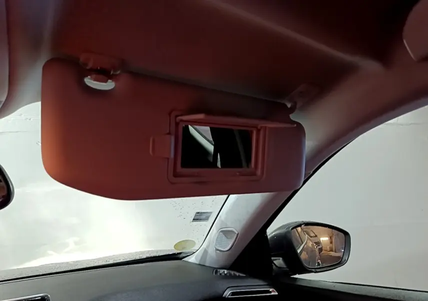 Vue intérieure côté conducteur du Peugeot 2008 gris clair 2021, avec pare-soleil et miroir de courtoisie ouverts.