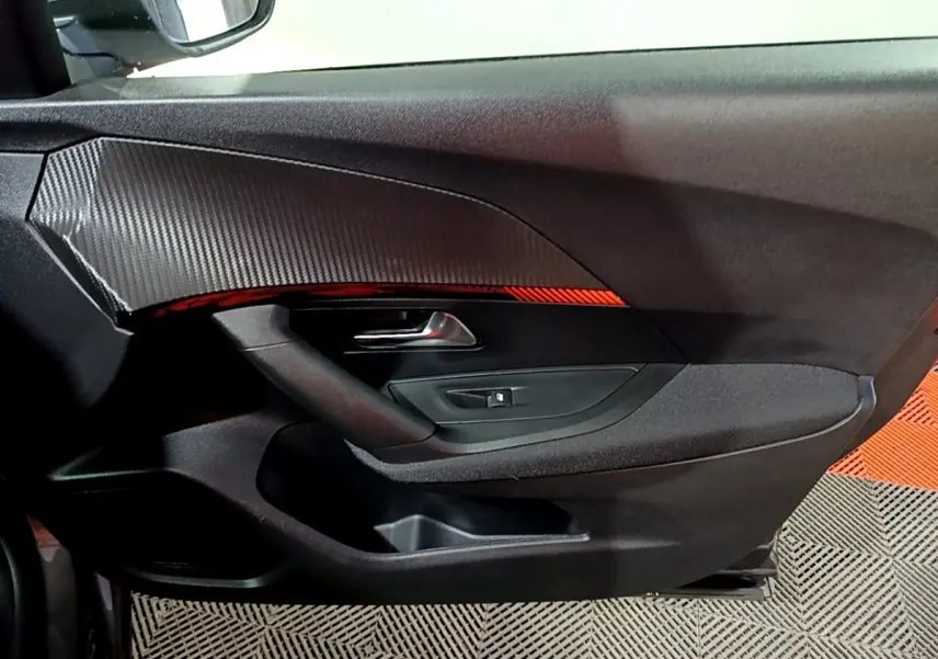 Intérieur côté gauche de porte PEUGEOT 2008 gris clair, avec poignée argentée et insert décoratif noir texturé.