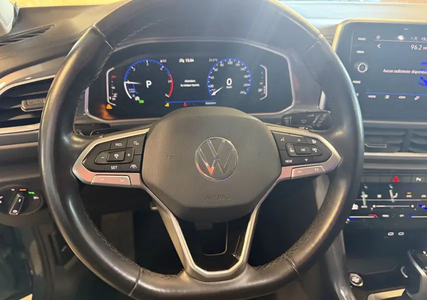 Vue rapprochée du volant noir de Volkswagen T-Roc 2.0 TDI 150 DSG7 avec tableau de bord numérique et écran central tactile.
