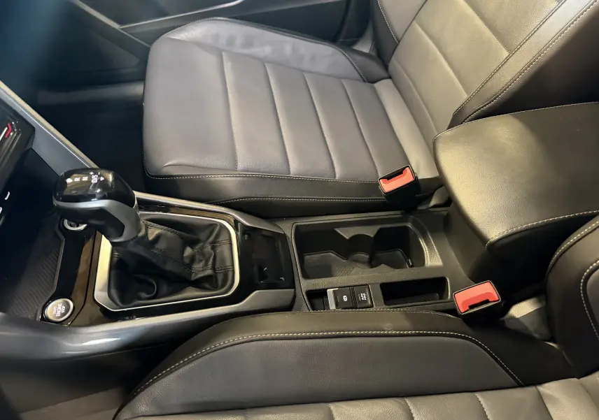 Vue intérieure rapprochée du levier de vitesses automatique et des sièges en cuir noir du Volkswagen T-Roc bleu.