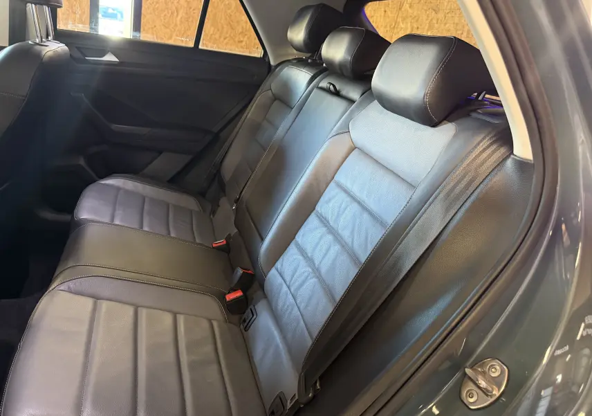 Vue intérieure arrière du Volkswagen T-Roc 2.0 TDI bleu, montrant les sièges arrière en cuir noir avec ceintures de sécurité.