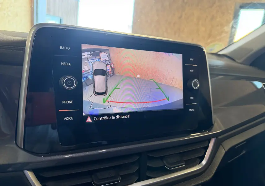 Écran central du Volkswagen T-Roc 2022 affichant la caméra de recul avec alertes de distance, intérieur noir visible.