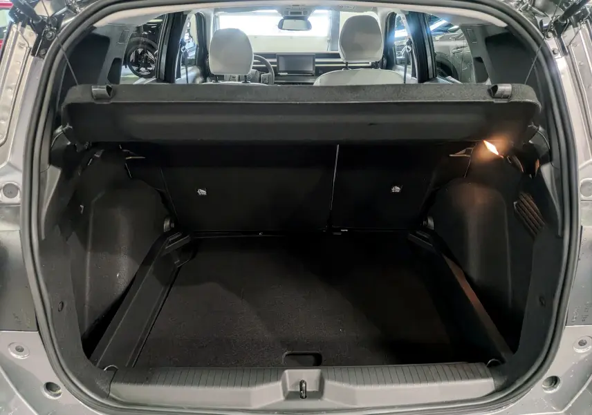 Coffre ouvert vu de l’arrière d’une Citroën C3 Aircross hybride gris Mercury avec toit noir, intérieur sombre et banquette arrière visible.