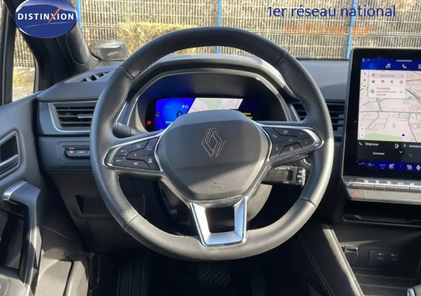 Vue intérieure centrée sur le volant de la Renault Symbioz gris cassiopée, avec tableau de bord digital et écran tactile à droite.