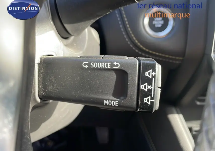 Gros plan sur la commande au volant avec boutons source et mode, intérieur noir du Renault Symbioz gris cassiopée métal.