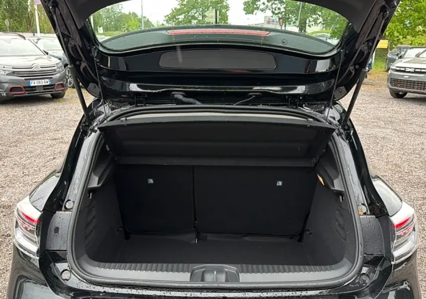 Coffre ouvert vu de l'arrière d'une Renault Clio V noire, montrant l'espace de chargement vide et les feux arrière LED.