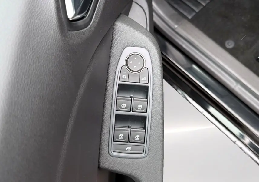 Vue rapprochée des commandes des vitres électriques sur la porte côté conducteur d’une Renault Clio V noire.