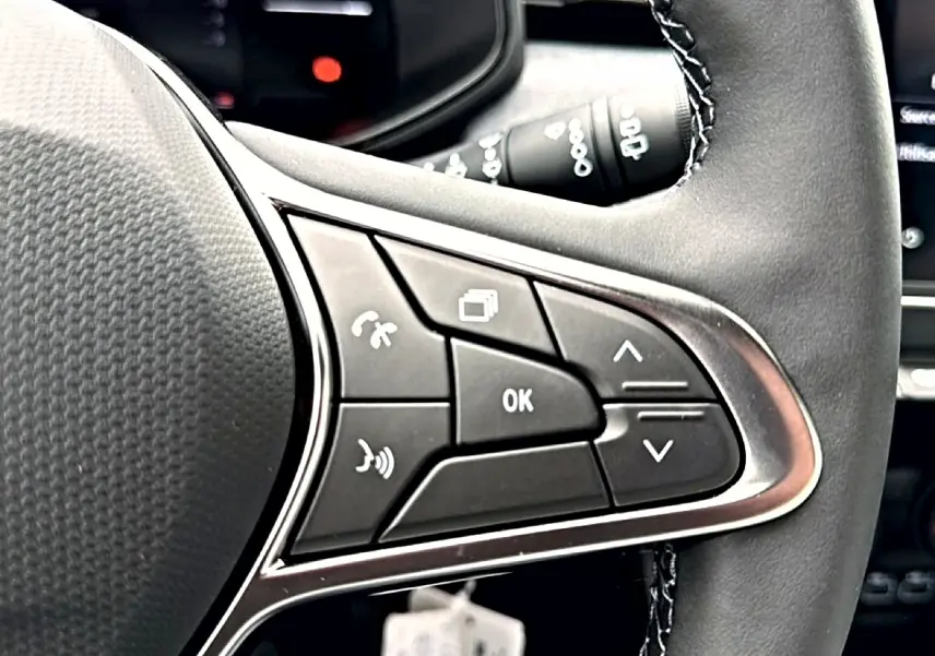 Gros plan sur les commandes multifonctions à droite du volant cuir de la Renault Clio V noire, avec boutons de navigation et appel.