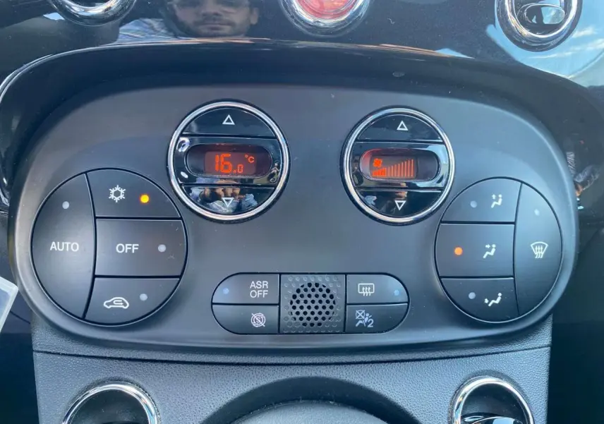Panneau de commande de climatisation digitale de la Fiat 500 noire, affichant 16°C et réglage de ventilation actif.