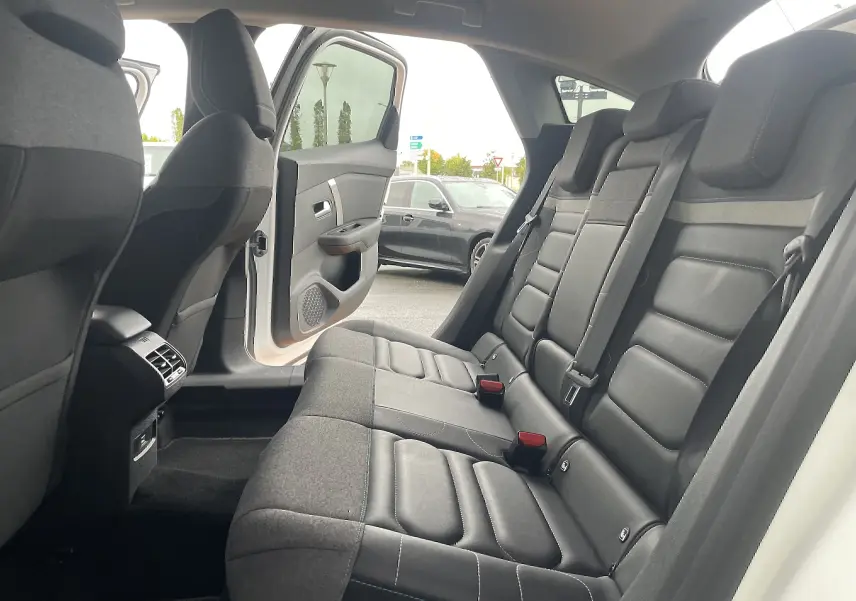 Vue intérieure côté droit des sièges arrière gris foncé en tissu de la Citroën C4 blanche avec porte arrière ouverte.