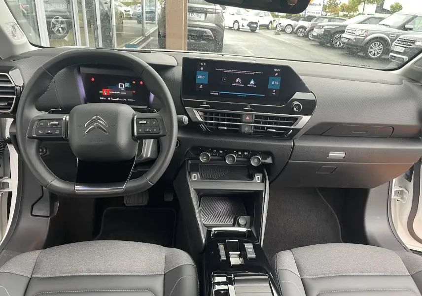 Vue intérieure avant de la Citroën C4 blanche 2022, tableau de bord moderne avec écran tactile et volant multifonction.