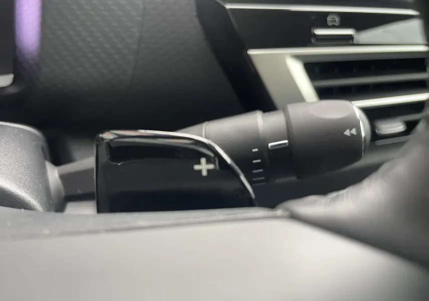 Gros plan sur la palette de changement de vitesse droite noire brillante dans l’habitacle gris foncé d’une Citroën C4 blanche 2022.