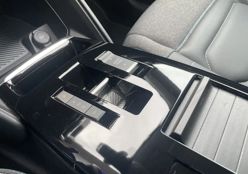 Gros plan sur la console centrale noire brillante de la Citroën C4 blanche, avec levier de vitesses automatique et siège tissu gris.