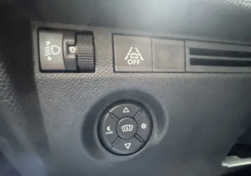 Détail des commandes d’éclairage et d’aide à la conduite sur le tableau de bord noir d’une Citroën C4 blanche.