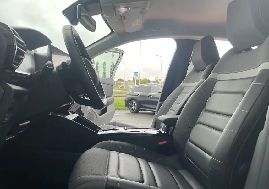 Vue intérieure côté gauche de la Citroën C4 2022, sièges tissu gris noir et volant multifonction visible.