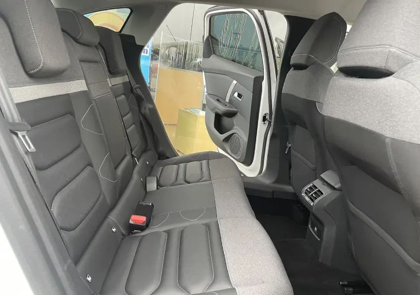 Vue intérieure arrière côté gauche d'une Citroën C4 blanche 2022, sièges tissu gris noir avec porte arrière ouverte.