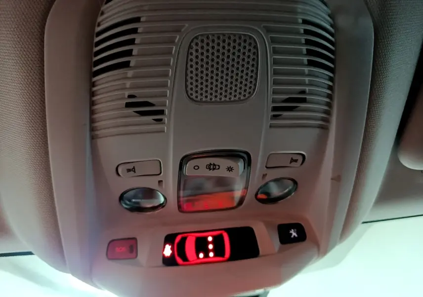 Vue intérieure en gros plan du plafonnier gris avec commandes d’éclairage et bouton SOS du Peugeot 3008 noir 2022.