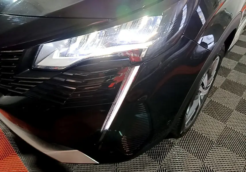 Gros plan sur l'avant droit noir du Peugeot 3008 2022 avec phares LED allumés et calandre distinctive.