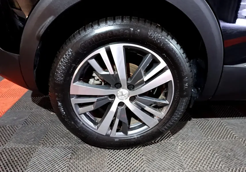 Gros plan sur la roue avant droite du Peugeot 3008 noir, avec jante alliage et pneu Continental visible.