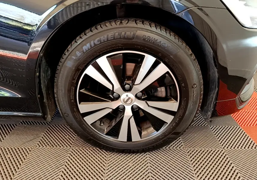 Gros plan sur la roue avant gauche noire d'une Volvo V60 2020 avec jante alliage bicolore et pneu Michelin.