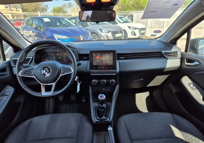 Vue intérieure avant de la Renault Clio V TCe 90 Equilibre 2022, tableau de bord noir avec écran tactile et boîte manuelle.