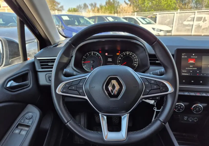 Vue intérieure centrée sur le volant noir de la Renault Clio 2022, avec tableau de bord et écran multimédia visibles.