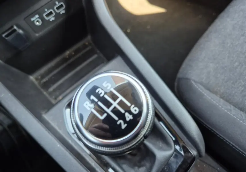 Gros plan sur le levier de vitesses manuel noir de la Renault Clio V TCe 90 Equilibre, intérieur tissu gris visible.