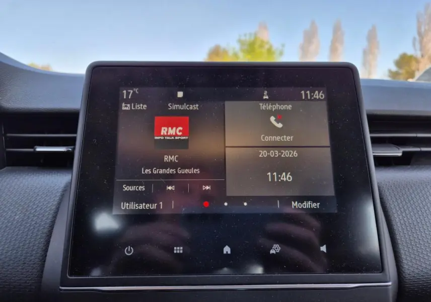 Écran tactile central de la Renault Clio V TCe 90 noir, affichant la radio RMC et les options téléphone.