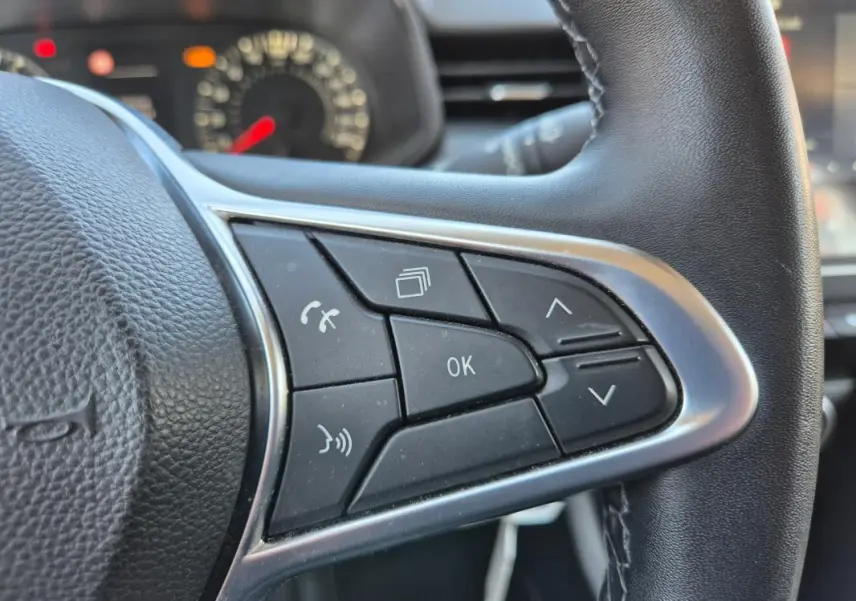 Gros plan sur les commandes multifonctions à droite du volant d’une Renault Clio noire, version V TCe 90 Equilibre.