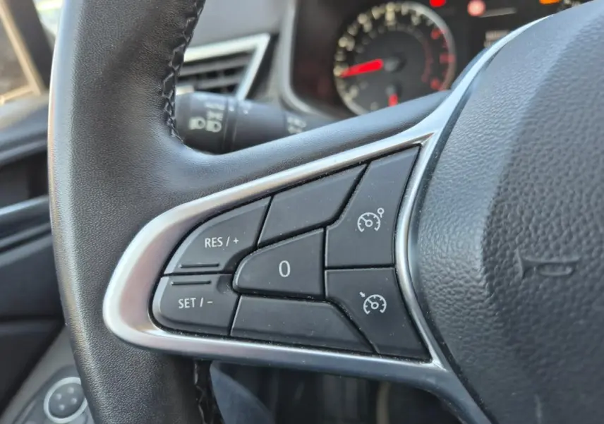 Gros plan sur les commandes du régulateur de vitesse au volant noir de la Renault Clio V TCe 90 Equilibre 2022.