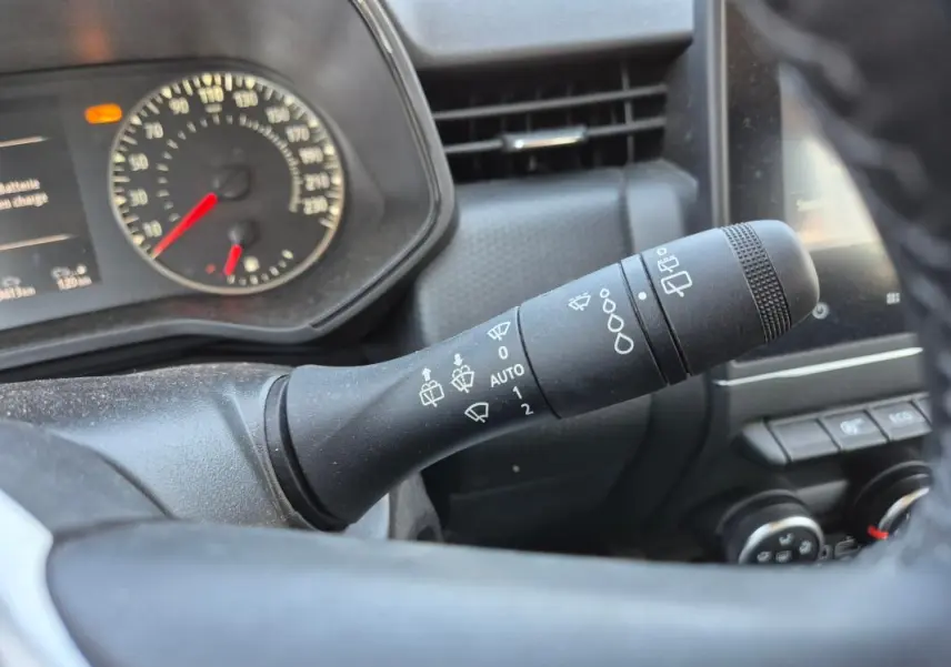 Gros plan sur la commande de détecteur de pluie à droite du volant d’une Renault Clio noire, tableau de bord en arrière-plan.