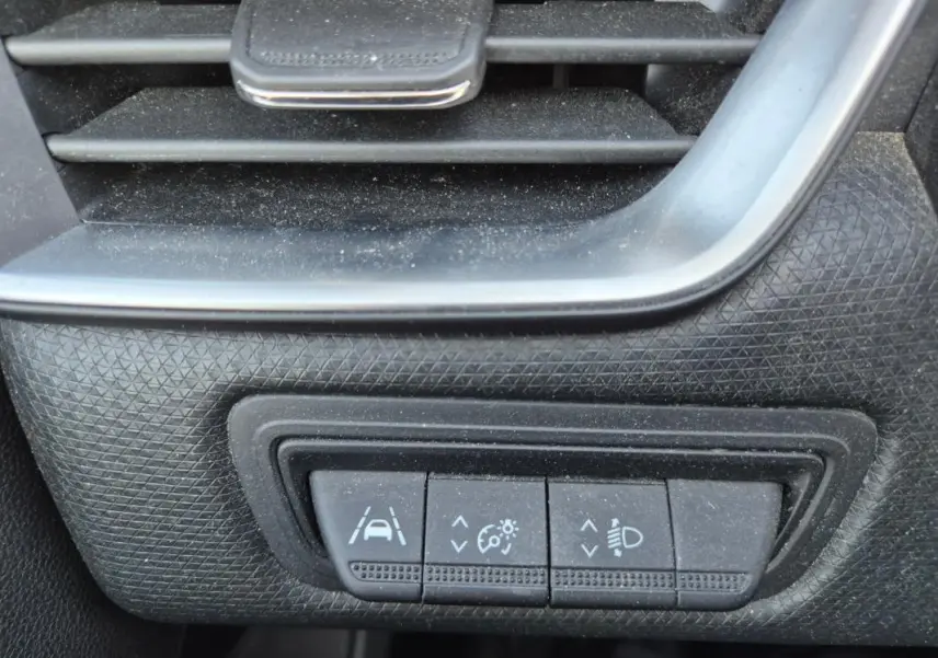 Gros plan sur les commandes de réglage d'assistance à la conduite et éclairage dans une Renault Clio noire 2022.