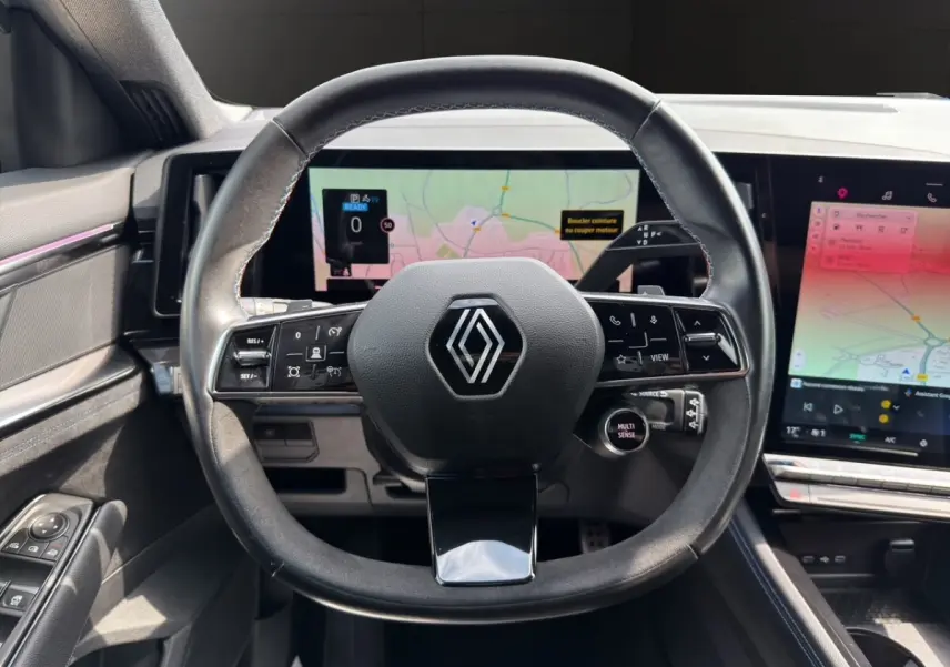 Vue intérieure centrée sur le volant cuir et suède avec logo Renault, écran tactile et tableau de bord numérique du Renault Espace 2024.