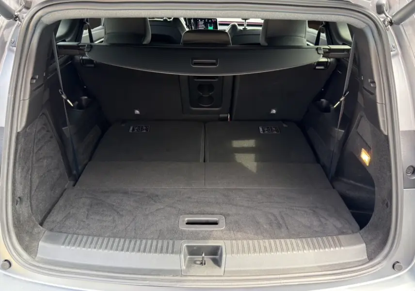 Coffre ouvert d’un Renault Espace gris foncé, vue arrière montrant les sièges arrière rabattus et la tablette cache-bagages.