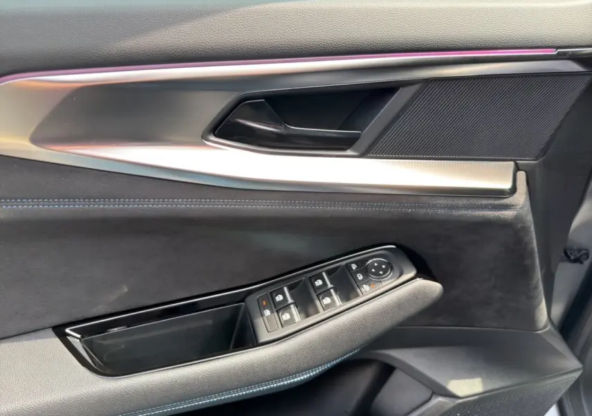 Détail de la porte côté conducteur du Renault Espace gris foncé, avec commandes électriques des vitres et éclairage d'ambiance violet.