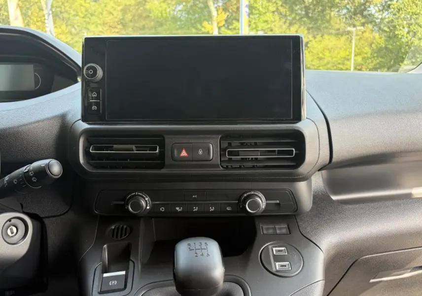 Vue rapprochée de la console centrale intérieure du Peugeot Partner blanc, avec écran tactile et levier de vitesses manuel.