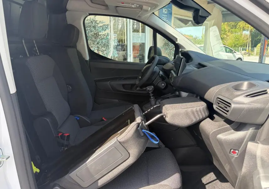 Vue intérieure côté passager du Peugeot Partner blanc 2026, montrant les sièges, le volant multifonctions et l’écran tactile GPS.