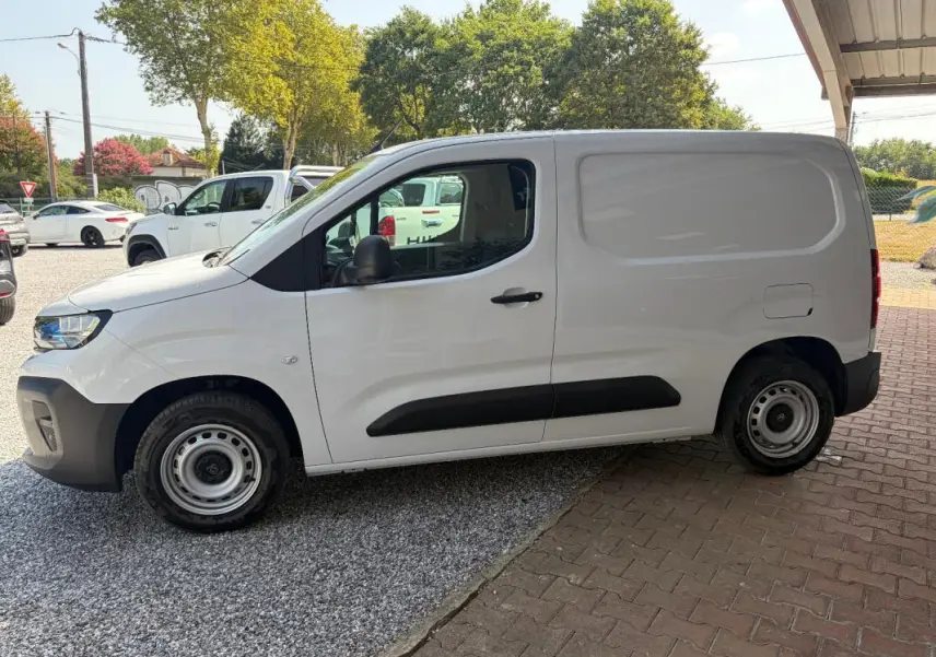 Peugeot Partner blanc vu de profil côté gauche, fourgon utilitaire avec protections noires sur les portières.