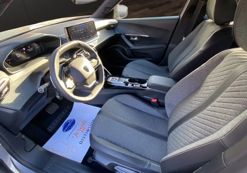 Vue intérieure côté conducteur du Peugeot 2008 2024 avec sièges tissu gris et tableau de bord moderne.