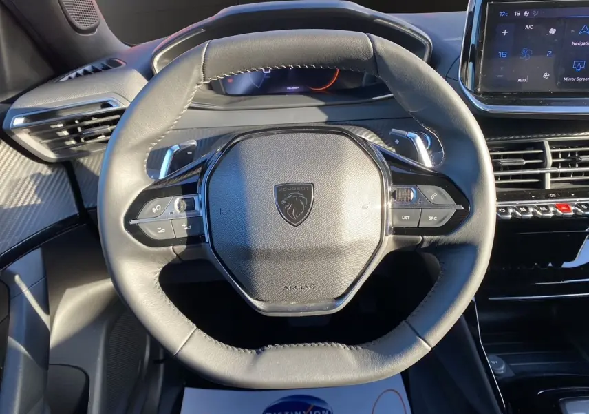 Vue rapprochée du volant cuir noir du Peugeot 2008 2024 avec commandes intégrées et tableau de bord numérique.
