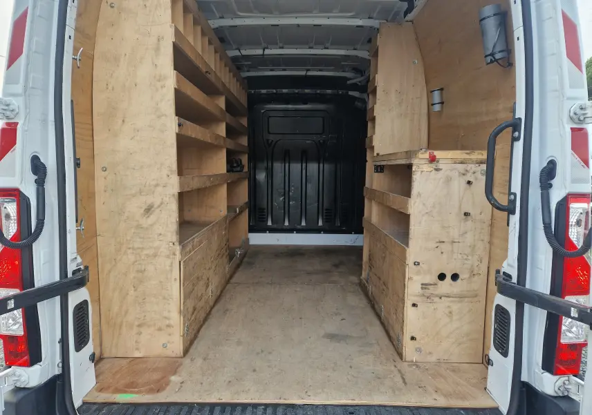 Vue arrière intérieure du Renault Master blanc 2020 avec aménagements en bois et étagères intégrées.