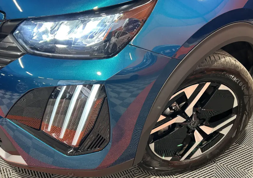 Gros plan sur l’avant droit bleu obsession du Peugeot 2008 Allure Hybrid 145, avec phares LED et jante noire et argent.