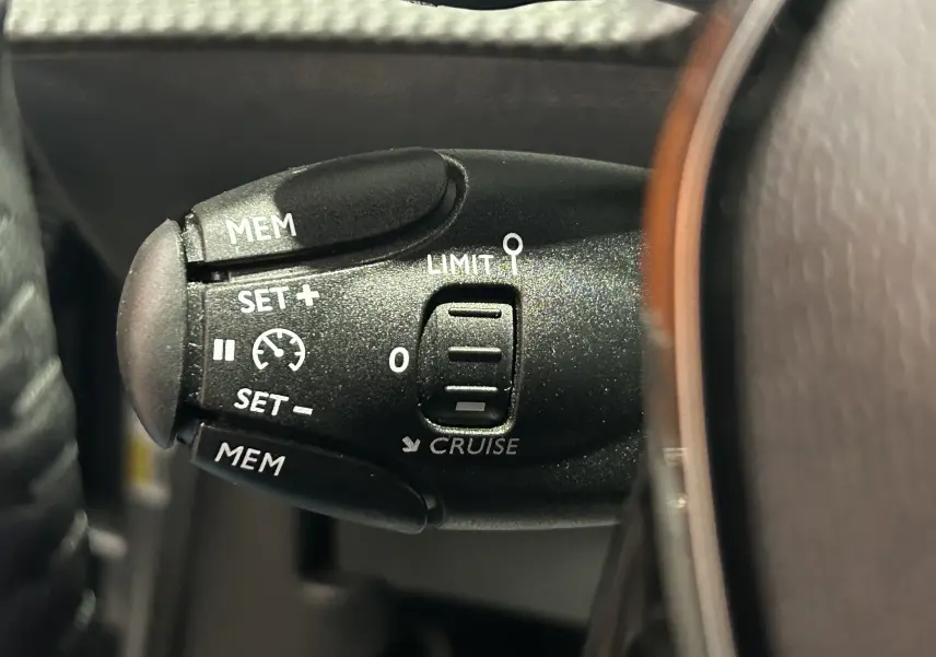 Gros plan sur la commande de régulateur de vitesse au volant d’une Peugeot 2008 Allure Hybrid 145 bleu Obsession.